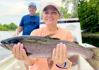 A woman showing a rainbow trout caught during a fishing trip