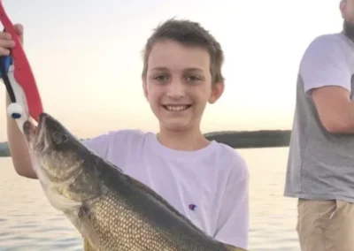 Young angler holding a walleye on a fishing boat