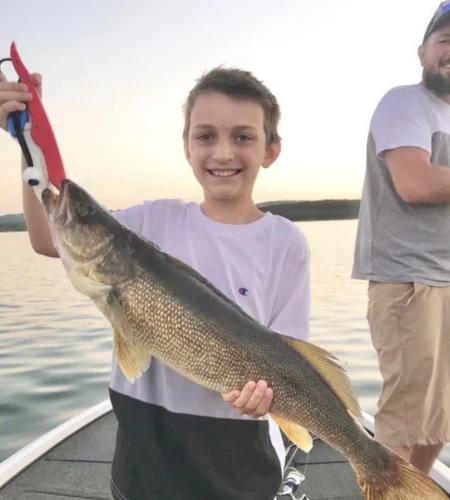 Young angler holding walleye on a Branson guided fishing boat