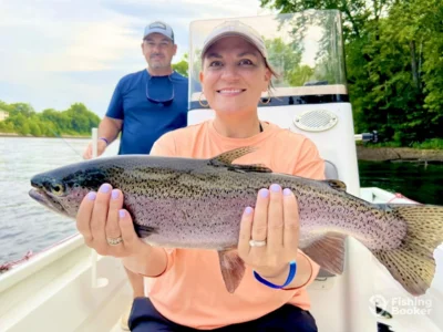 A woman holding a rainbow trout during a fishing trip
